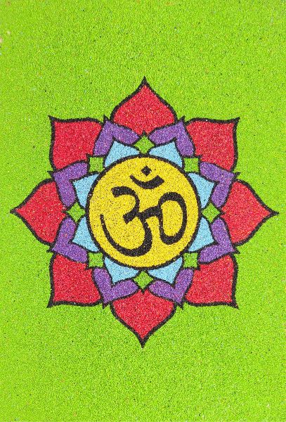 Ohm homokkép with colorful sand art design on green background.